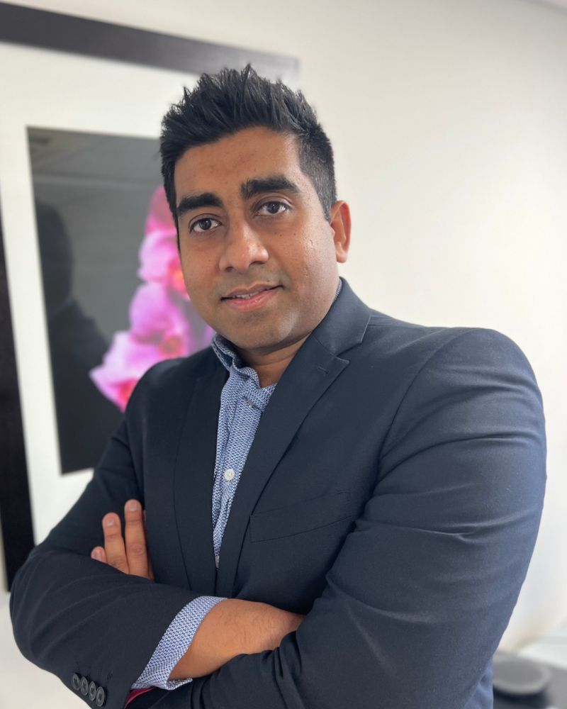 Mr Sarker looking into camera with arms crossed wearing a dark jacket
